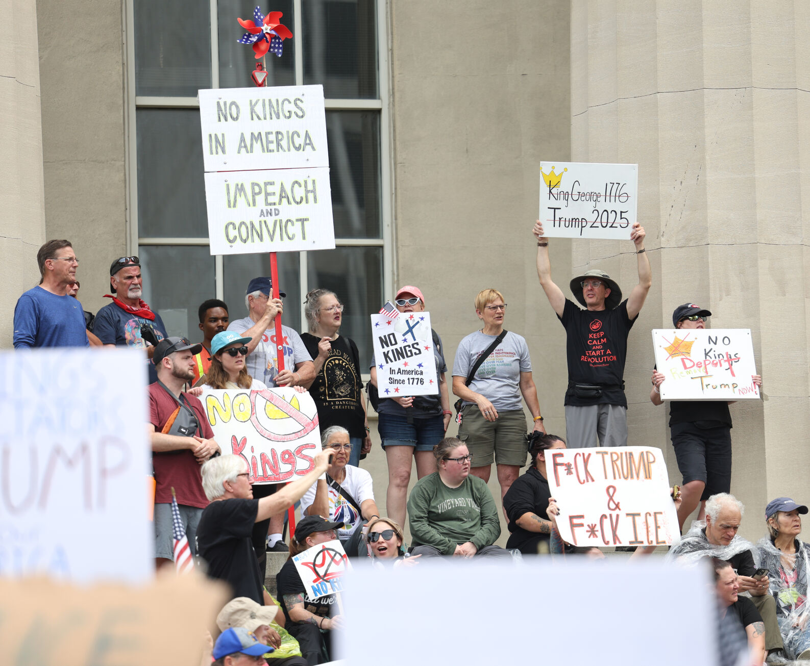 People hold up signs at steps of Metro Hall.JPG